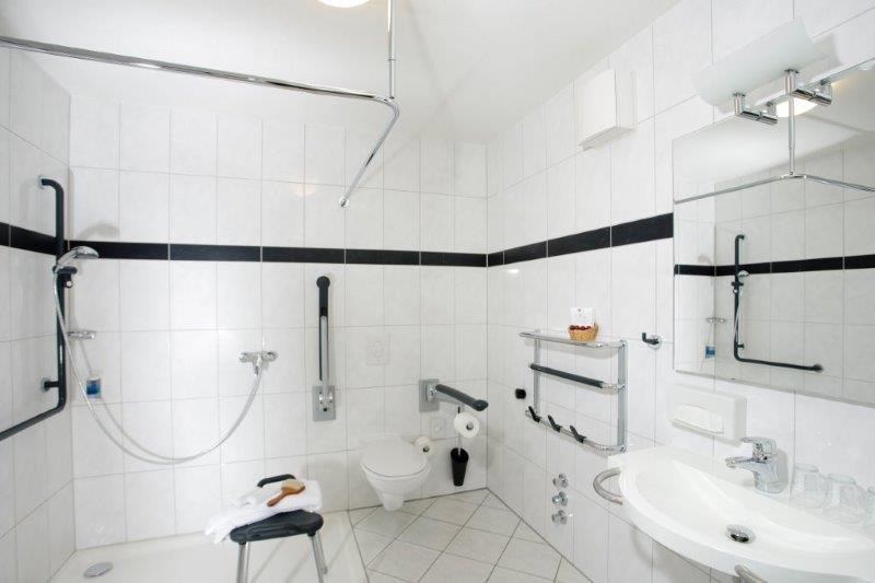 Rollstuhlgerechte Dusche und verstellbare Stützklappgriffe am WC im Aparthotel Steiger