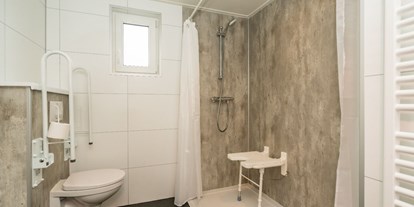 Rollstuhlgerechte Unterkunft - Niederlande - Die Dusche hat einen Sitz und Haltegriffe, einen unterfahrbaren Waschtisch und einen höhenverstellbaren Spiegel. Das Dusch-WC hat klappbare Stützen. Im Flur des Hauses befindet sich noch eine separate Toilette. - Rollstuhl Urlaub in Zeeland - De Klaproos