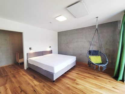 Rollstuhlgerechte Unterkunft - Unterkunftsart: Ferienwohnung - erstes Schlafzimmer mit Doppelbett (1,80m x 2,00m) Boxspringbett und Hängesessel - Erdhausapartment WEST