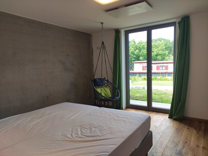 Rollstuhlgerechte Unterkunft - Bayern -  erstes Schlafzimmer mit Doppelbett und ebenerdiger Ausgang auf die Terrasse - Erdhausapartment WEST